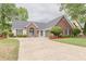 Charming single-story home with brick and siding exterior, a manicured lawn, and an expansive driveway at 4565 English Oaks Ln, Lilburn, GA 30047