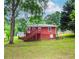 Rear view of a red home with a backyard, highlighted by lush trees and sky at 551 Barnes Mill Dr, Marietta, GA 30062