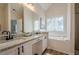 Well-lit bathroom featuring a granite vanity top, double sinks, large mirror, and soaking tub at 861 Soaring Dr, Marietta, GA 30062