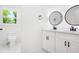 Modern bathroom featuring double vanity, round mirrors, black fixtures, and a toilet with white tiling at 2263 Barge Rd, Atlanta, GA 30331