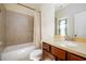 Well-lit bathroom featuring a shower and tub combination with neutral tile, light countertops and wood cabinetry at 6110 Read Rd, Suwanee, GA 30024