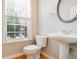 Cozy half-bathroom featuring a pedestal sink, a round mirror, and natural light at 4087 Kingsley Park Ct, Peachtree Corners, GA 30096