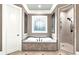Elegant bathroom featuring a soaking tub, frameless shower, and decorative window at 13037 Overlook Pass, Roswell, GA 30075