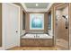Luxurious bathroom with soaking tub, shower, decorative window and neutral tile surround at 13037 Overlook Pass, Roswell, GA 30075