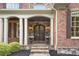 Elegant brick home entrance with stone steps, arched doorway, and classic flower planters at 13037 Overlook Pass, Roswell, GA 30075