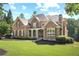 Beautiful brick home featuring a covered porch, manicured lawn, and mature landscaping at 13037 Overlook Pass, Roswell, GA 30075