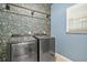 Well-equipped laundry room with modern washer and dryer, featuring stylish wallpaper and ample space at 1037 Panoramic Pte, Buford, GA 30518