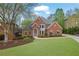 Beautiful brick home showcasing mature trees, a well-maintained lawn, and lovely curb appeal at 1025 Saint Marks Walk, Suwanee, GA 30024