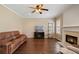 Comfortable living room boasts hardwood floors, a ceiling fan, a fireplace, and a leather sofa at 3235 Northcliff Dr, Suwanee, GA 30024
