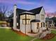Gorgeous modern home with black roof accents, white brick, and lush green lawn and landscaping at 56 Pine St, Roswell, GA 30075