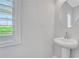 A modern powder room with a pedestal sink, round mirror, and plantation shutters for natural light at 1768 Evenstad Way, Smyrna, GA 30080