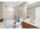 Bathroom featuring a shower-tub combo, light tile, and single sink vanity at 2041 Democracy Dr, Buford, GA 30519