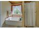 Inviting bathtub with a large window, providing natural light and a serene atmosphere at 3870 Michaels Creek Ct, Loganville, GA 30052