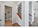Hallway with hardwood floors leading to a staircase with wood railing and an open door to a half bathroom at 505 Rendezvous Rd, Acworth, GA 30102