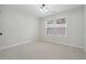 A clean, empty bedroom featuring neutral walls and carpet with natural light from the window at 1736 Dylan Pl, Lawrenceville, GA 30043