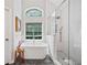 A bathtub sits beneath an arched window, adjacent to a tiled shower in this modern bathroom at 111 Jeffrey Pl, Smyrna, GA 30082