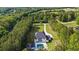 An aerial view of the home with a pool, long driveway and surrounding lush forest at 2400 Worth Ave, Loganville, GA 30052
