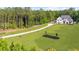 Long driveway leads to a two-story home surrounded by well-maintained lawn and a backdrop of tall trees at 2400 Worth Ave, Loganville, GA 30052