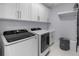 Bright laundry room with white cabinets, modern washer and dryer, and convenient storage solutions at 2400 Worth Ave, Loganville, GA 30052