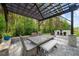 Outdoor dining area with a pergola, built-in grill, dining table, and lush backyard at 2400 Worth Ave, Loganville, GA 30052