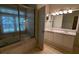 Bright bathroom featuring a double sink vanity, tiled floor, and glass enclosed tub with jacuzzi at 345 Deerwood Dr, Suwanee, GA 30024