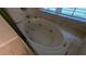 Close-up of a jacuzzi tub with jets and a window view, tiled in neutral colors at 345 Deerwood Dr, Suwanee, GA 30024