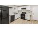 Modern kitchen featuring white cabinets, granite countertops, and black appliances at 6864 Maddox Rd, Morrow, GA 30260