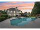 Backyard with a refreshing pool, spacious patio for lounging, enclosed porch, and landscaped surroundings at 1225 Elk Ridge Cv, Alpharetta, GA 30005