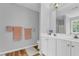 Bright bathroom with a double sink vanity, large mirror, white cabinets and wood-look floors at 190 Crestworth Ct, Powder Springs, GA 30127