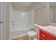 Bright bathroom featuring white tiled tub and shower, white toilet, and red vanity at 3071 Springfair Trott, Lithonia, GA 30038