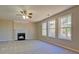 Carpeted living room featuring a fireplace, ceiling fan, and three large windows for natural light at 3071 Springfair Trott, Lithonia, GA 30038