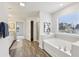 Bright bathroom featuring a soaking tub, wood-look flooring, and a large window with backyard views at 1451 Stephens View Dr, Loganville, GA 30052