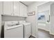 Bright laundry room features a modern washer and dryer set and a large storage cabinet at 1451 Stephens View Dr, Loganville, GA 30052