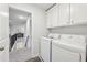 Hallway laundry area featuring white washer and dryer units, plus upper storage cabinets at 1451 Stephens View Dr, Loganville, GA 30052