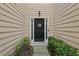 Close up of a welcoming front door surrounded by manicured landscaping and wood siding at 7077 Biltmore Trce, Lithonia, GA 30058