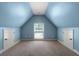 Attic room with angled ceilings, painted in a serene blue, featuring two access doors and a central window at 7251 Bluewater Ln, Douglasville, GA 30135