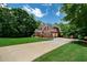Long concrete driveway leading to a brick home with attached garage, lush lawn and mature trees at 7251 Bluewater Ln, Douglasville, GA 30135