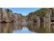 View of a serene lake reflecting the surrounding trees and blue sky on a sunny day at 295 Lakemont Dr, Roswell, GA 30075