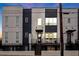 Modern townhome facade features a black iron gate, contrasting gray siding, and a charming front porch with ample light at 687 Banton Nw Dr, Atlanta, GA 30318