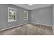 Cozy bedroom featuring neutral gray walls, carpeted floors, and two bright windows for natural light at 9480 Coleman Rd, Roswell, GA 30075