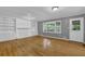 Open living room with wood floors, a painted brick fireplace and built in shelving at 9480 Coleman Rd, Roswell, GA 30075