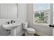 Bathroom featuring a white pedestal sink, toilet and a sunlit window offering a view of the surroundings at 2631 Creekside Nw Dr, Atlanta, GA 30318