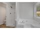 Bathroom featuring a shower and tub combination with all-white finishes and natural light from a window at 5383 Biffle Way, Stone Mountain, GA 30088