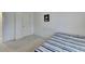 A minimalist bedroom with white walls, carpeted floor, a single bed with a striped blue and white cover and a small poster on the wall at 2132 Arnage Dr, Lithonia, GA 30058