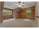 Spacious bedroom featuring log walls, neutral carpet, and natural light from multiple windows at 6605 Old White Mill Rd, Fairburn, GA 30213