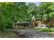 Beautiful two-story log home with a covered front porch surrounded by lush greenery at 6605 Old White Mill Rd, Fairburn, GA 30213