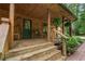 Welcoming log-sided porch with rocking chairs, a green door, and steps leading up, enhanced by plants at 6605 Old White Mill Rd, Fairburn, GA 30213