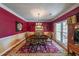 Elegant dining room with rich red walls, crown molding, and a large window for natural light at 12 Blackfoot Trl, Sharpsburg, GA 30277