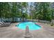 Backyard pool with a diving board, concrete surround, and a white fence surrounded by trees at 12 Blackfoot Trl, Sharpsburg, GA 30277