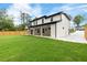 Expansive backyard featuring a modern white home with large windows and a covered patio at 1349 Oak Road, Lilburn, GA 30047